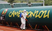 A official wearing PPE sprays the players bench with disinfectant spray before the African Cup of Nations 2022 group F soccer match between Tunisia and Mali at the Limbe Omnisport Stadium in Limbe, Cameroon, Wednesday, Jan. 12, 2022. (AP Photo/Sunday Alamba)