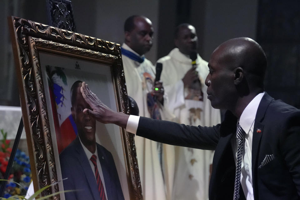 A mourner reaches out to touch a photograph of Haiti's assassinated President Jovenel Moïse, during a memorial service at Notre Dame d'Haiti Catholic Church on Thursday, July 22, 2021, in the Little Haiti neighborhood of Miami. Miami's Haitian Consul General hosted the service for members of the city's large Haitian community to pray for the troubled nation and pay their respects to the president, who was slain in a July 7 attack at his home which left his wife seriously wounded.(AP Photo/Rebecca Blackwell)