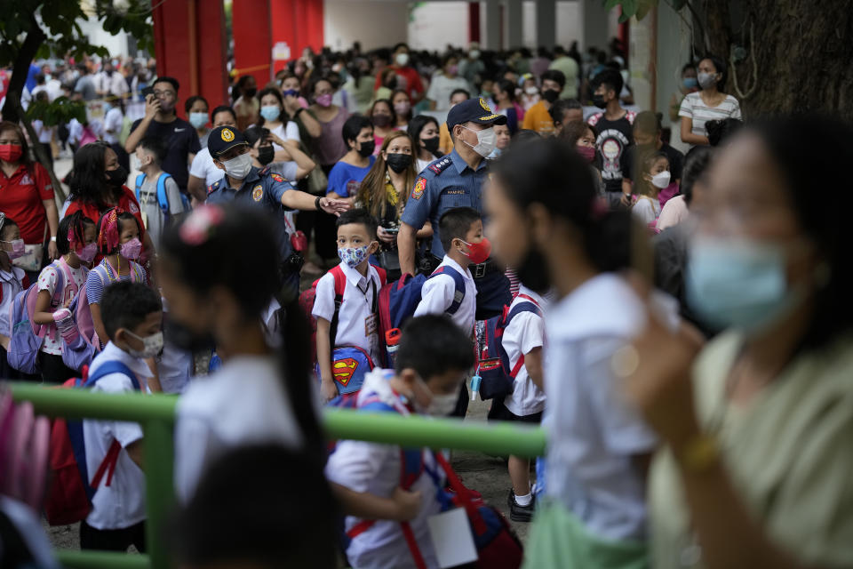 Students and parents gather during the opening of classes at the San Juan Elementary School in metro Manila, Philippines on Monday, Aug. 22, 2022. Millions of students wearing face masks streamed back to grade and high schools across the Philippines Monday in their first in-person classes after two years of coronavirus lockdowns that are feared to have worsened one of the world's most alarming illiteracy rates among children. (AP Photo/Aaron Favila)