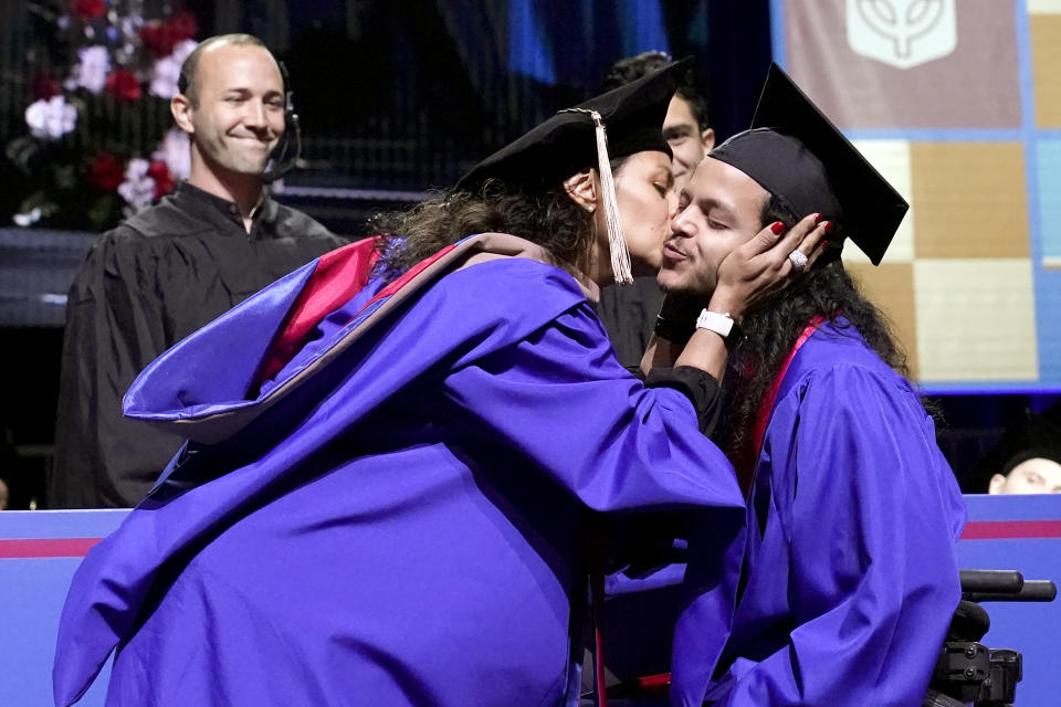 Herlinda Annicks kisses her son Jonathan after presenting him with the cover for his bachelor's degree in communications and media at DePaul University's graduation ceremonies Sunday, June 12, 2022, in Chicago. Shortly after receiving the cover Jonathan presented her with the cover for her Masters of Business Administration. (AP Photo/Charles Rex Arbogast)
