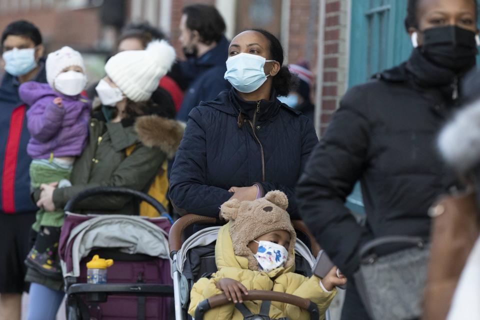 FILE - Makda Yesuf, center, and her son Jaden wait in line at a COVID-19 walk-in testing site, Dec. 5, 2021, in Cambridge, Mass. Even as the U.S. reaches a COVID-19 milestone of roughly 200 million fully-vaccinated people, infections and hospitalizations are spiking, including in highly-vaccinated pockets of the country like New England. (AP Photo/Michael Dwyer, File)