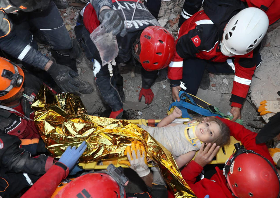 In this photo provided by the government's Search and Rescue agency AFAD, rescue workers, who were trying to reach survivors in the rubble of a collapsed building, surround Ayda Gezgin in the Turkish coastal city of Izmir, Turkey, Tuesday, Nov. 3, 2020, after they have pulled the young girl out alive from the rubble of a collapsed apartment building four days after a strong earthquake hit Turkey and Greece. The girl, Ayda Gezgin, was seen being taken into an ambulance on Tuesday, wrapped in a thermal blanket, amid the sound of cheers and applause from rescue workers.(AFAD via AP)