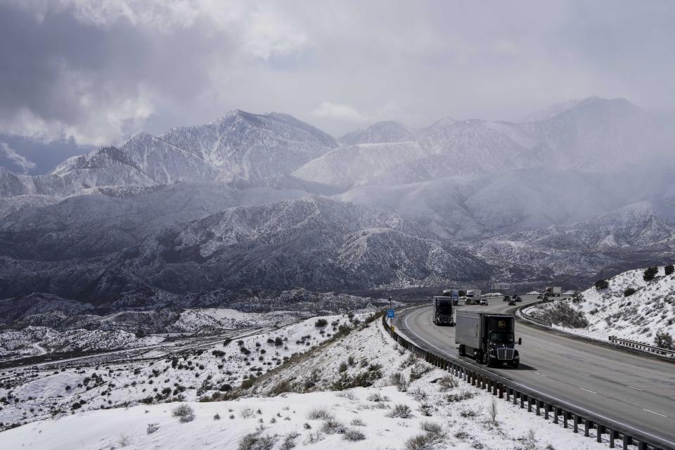 Vehicles make their way along the I-15 as clouds pass through the snow-covered mountains near Hesperia, Calif., Wednesday, March 1, 2023. (AP Photo/Jae C. Hong)