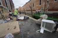 People remove damaged items from an alley in Venice, northern Italy, Monday, Nov. 18, 2019. Venetians have been coping with almost a week of exceptional tides that flooded most of the city and caused damage that has been estimated at hundreds of millions of euros (dollars). (Andrea Merola/ANSA via AP)