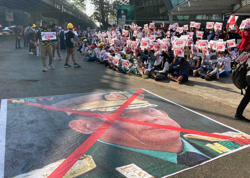 A large image that has an X mark on the face of Commander in chief Senior Gen. Min Aung Hlaing, also chairman of the State Administrative Council, lies on a road as anti-coup protesters gather outside the Hledan Centre in Yangon, Myanmar, Sunday, Feb. 14, 2021. Daily mass street demonstrations in Myanmar are on their second week, with neither protesters nor the military government they seek to unseat showing any signs of backing down from confrontations. (AP Photo)