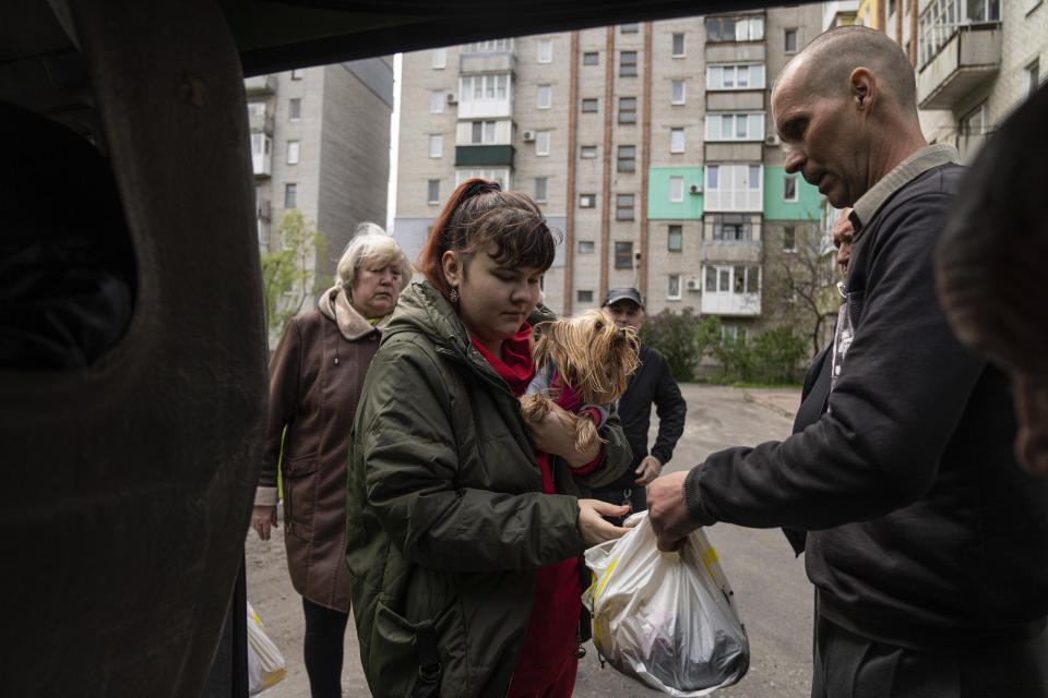 A woman receives humanitarian aid from a volunteer in Lyman, Donetsk region, eastern Ukraine, Saturday, April 30, 2022. (AP Photo/Evgeniy Maloletka)