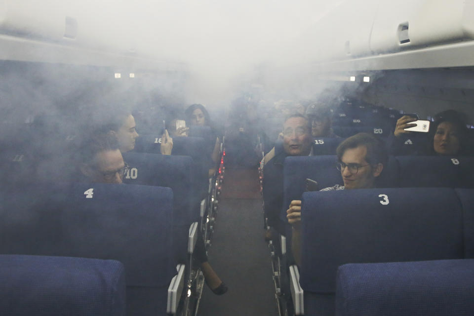 Members of the media participate in a demonstration of an airline cabin filling with smoke, in a simulator at the FAA Civil Aerospace Medical Institute in the Mike Monroney Aeronautical Center, Thursday, Oct. 17, 2019, in Oklahoma City. Federal researchers, using 720 volunteers in Oklahoma City, will test whether smaller seats and crowded rows slow down airline emergency evacuations. (AP Photo/Sue Ogrocki)