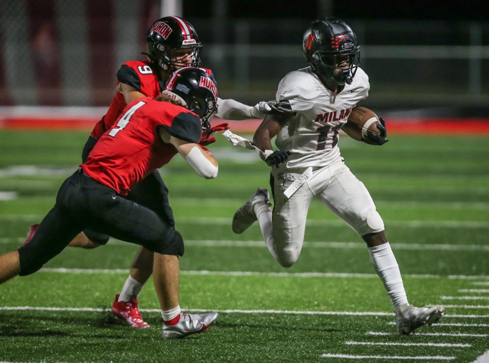 Milan's Ronny Johnson (11) is chased out of bounds by Huron's Ashton Warren (4) and Ryan Anderson during the fourth quarter Thursday, Sept. 1, 2022.