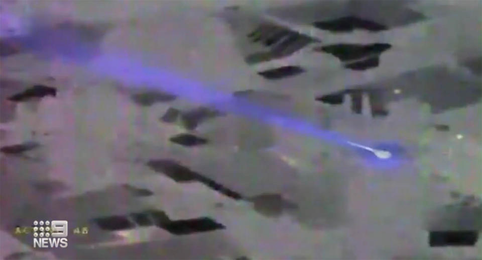 An aerial view of a laser pointed shining from a building below.  