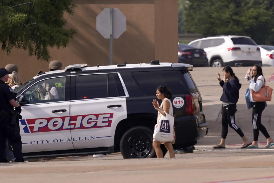 People raise their hands as they leave a shopping center after a shooting, Saturday, May 6, 2023, in Allen, Texas. (AP Photo/LM Otero)