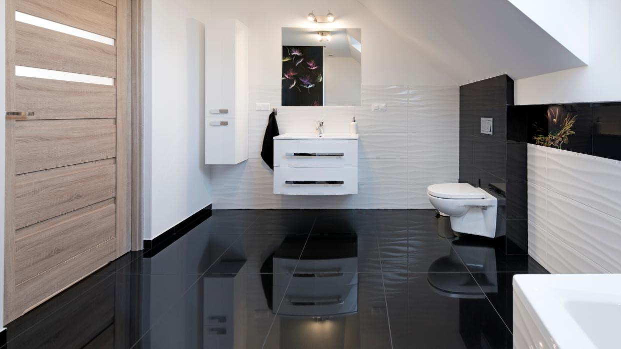  Gleaming bathroom with white wall sink and toilet reflected in shiny black floor tiles - for how to clean bathroom floors. 