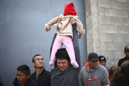 A Central American migrant caravan member holds a baby, as he lines up to receive breakfast at the end of his journey through Mexico, prior to preparations for an asylum request in the U.S., at a shelter in Tijuana, Baja California state, Mexico April 27, 2018. REUTERS/Edgard Garrido