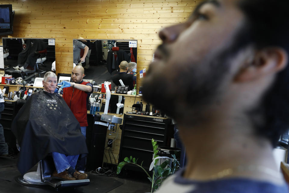 John Paul Garcia, de 20 años, a la derecha, espera su turno en el Blast Barber Studio/Barberia de Burlington, Carolina del Norte, el jueves 12 de marzo de 2020. (AP Foto/Jacquelyn Martin)