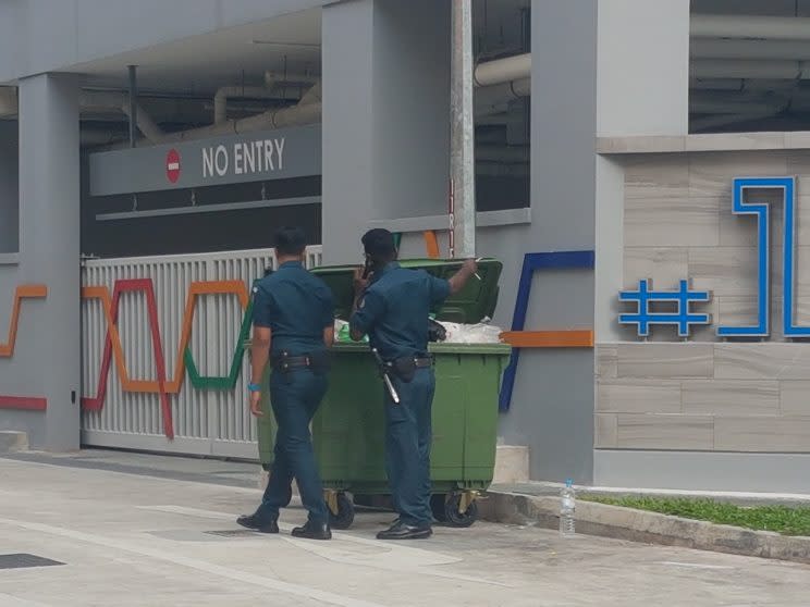 Auxiliary officers going through a dumpster as they look for contraband cigarettes at Lorong 6 Geylang. (Yahoo Singapore photo: Safhras Khan)