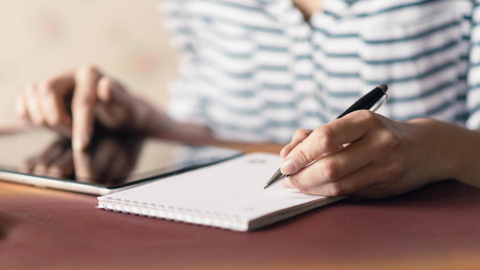 Woman Writing in a Notebook ant doing here job in home.