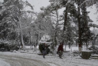 In this Sunday, Jan. 12, 2020, photo, people walk on a road during heavy snow fall in Quetta, capital of Pakistan's southwestern Baluchistan province. Much of the damage was caused in Pakistan's southwestern Baluchistan province where Imran Zarkon, the head of provincial disaster management authority said 14 people were killed in the past 24 hours because of roofs amid winter's unusual snowfall, which also blocked highways and disrupted normal life. (AP Photo/Arshad Butt)