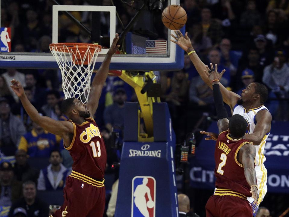 Golden State Warriors' Kevin Durant, right, lays up a shot against Cleveland Cavaliers' Tristan Thompson, left, and Kyrie Irving (2) during the first half of an NBA basketball game Monday, Jan. 16, 2017, in Oakland, Calif. (AP Photo/Ben Margot)