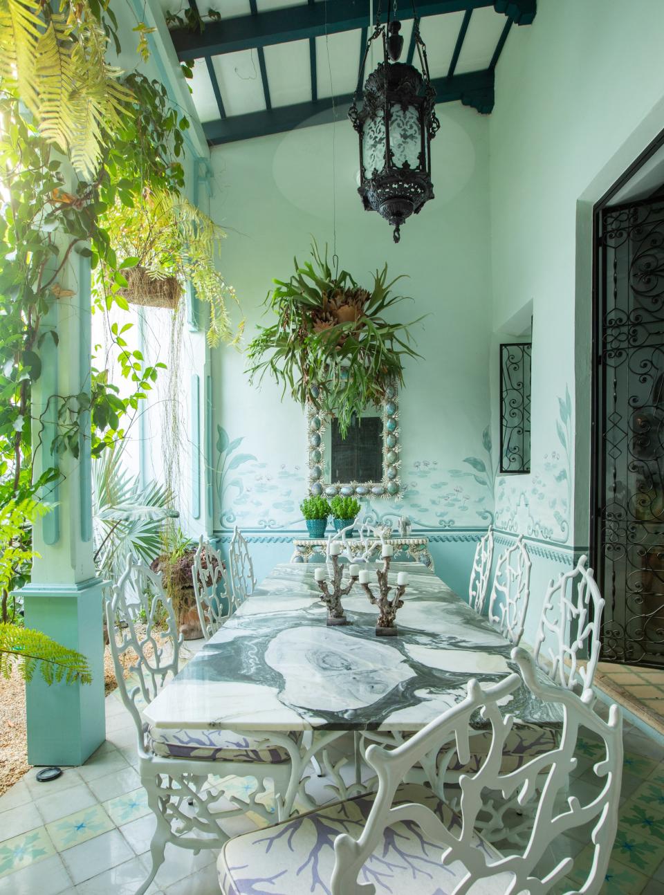 A patio with a botanical scene painted by local artisan Miguel Rivero. Skouras designed the iron-and-marble table, the mirror, and the console. The chairs are from her line for Currey & Company.