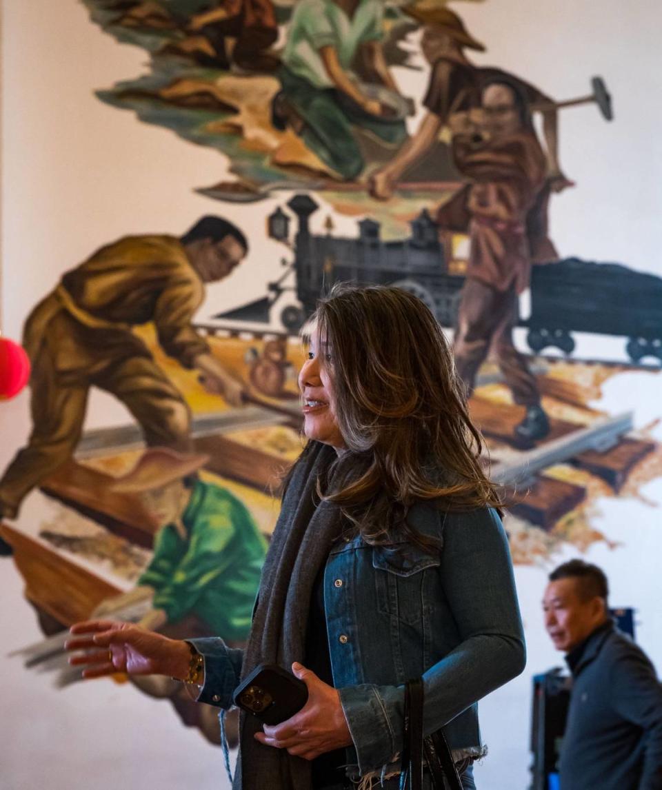 Susie Wong, a government affairs consultant who volunteers with the Chinese Consolidated Benevolent Association in Sacramento, talks about the Confucius Temple’s future while inside the building’s auditorium earlier this month. A large mural depicts the history of Chinese immigrants and Chinese Americans in California behind her.