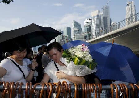 People pick up free umbrellas as they queue up to pay their respects to the late first prime minister Lee Kuan Yew at the Padang grounds outside the Parliament House in Singapore March 28, 2015. REUTERS/Edgar Su