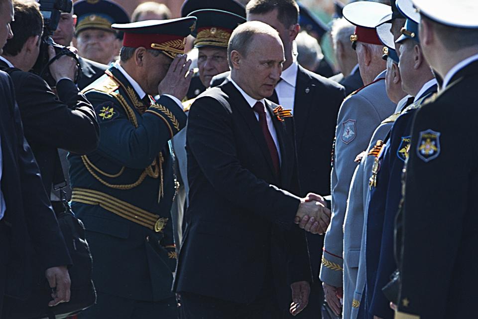 Russian President Vladimir Putin, center, shakes hands with WWII veterans as Defense Minister Sergei Shoigu, center left, salutes after the Victory Day Parade in Red Square in Moscow, Russia, Friday, May 9, 2014. Thousands of Russian troops march on Red Square in the annual Victory Day parade in a proud display of the nation's military might amid escalating tensions over Ukraine. (AP Photo/Pavel Golovkin)