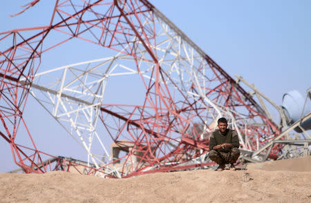 A Syrian Democratic Forces (SDF) fighter sits in front of a damaged tower ahead of an offensive against Islamic State militants in northern Deir al-Zor province, Syria February 21, 2017. REUTERS/Rodi Said