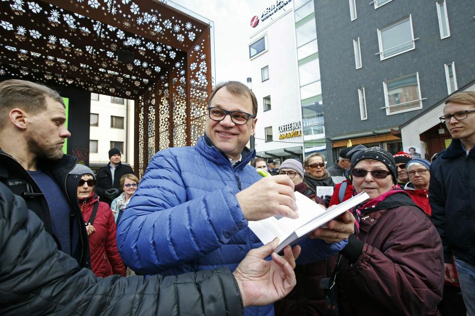 Chairman of the Centre Party and current Prime Minister Juha Sipila signs autographs as he campaigns for the Finnish parliamentary elections in Oulu, northern Finland, on Saturday, April 13, 2019. The election day of the Finnish parliamentary elections is on Sunday. (Timo Heikkala/Lehtikuva via AP)