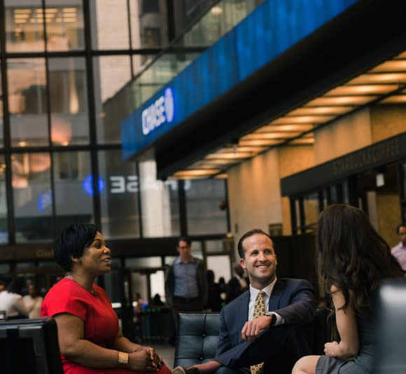 Three people talking among themselves while sitting in leather chairs in a Chase bank lobby.