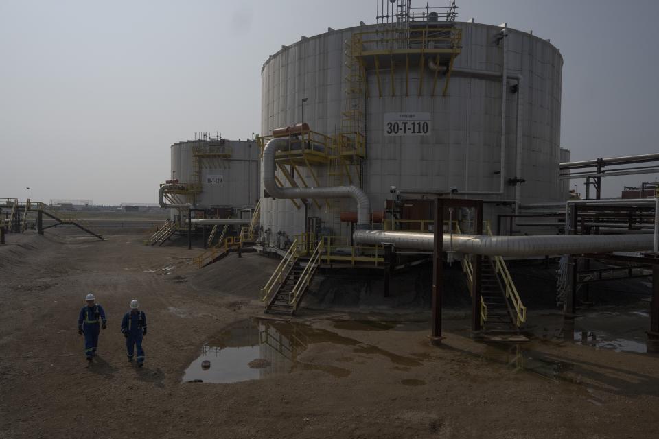 Workers walk by crude oil tanks at Cenovus' Sunrise oil facility northeast of Fort McMurray on Thursday, Aug. 31, 2023. (AP Photo/Victor R. Caivano)