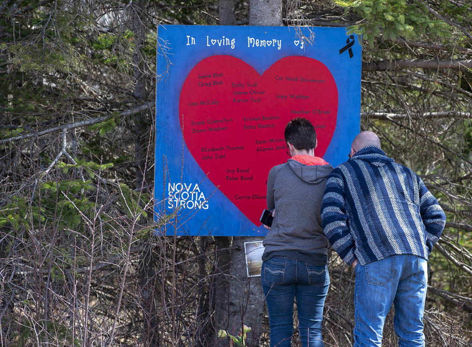 People pay their respects at a roadside memorial in Portapique, Nova Scotia on Sunday, April 26, 2020. A man went on a murder rampage in Portapique and several other Nova Scotia communities killing 22 people. (Andrew Vaughan/The Canadian Press via AP)