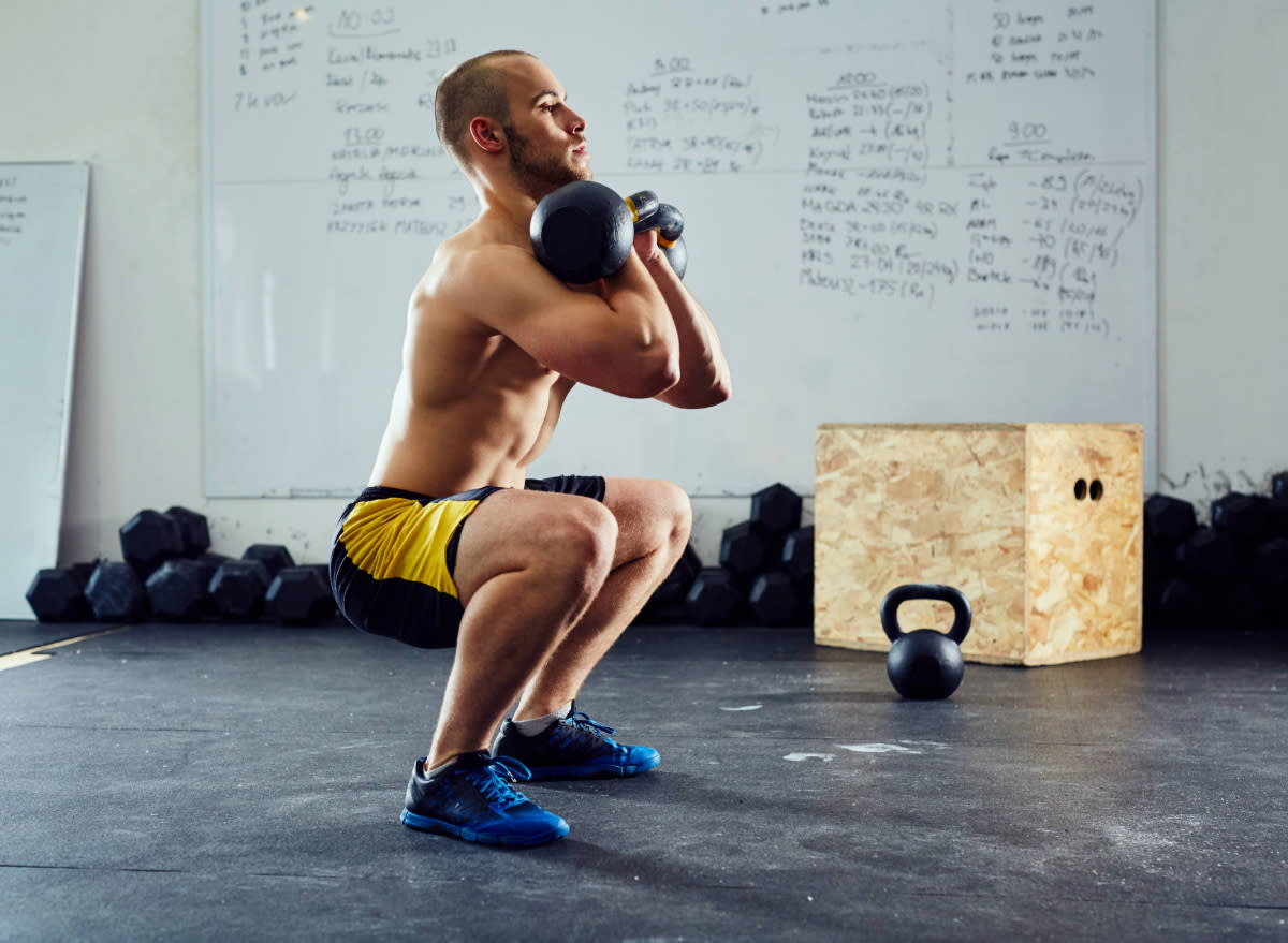 fit muscular man doing kettlebell squats, concept of kettlebell leg workout to build muscle and strength