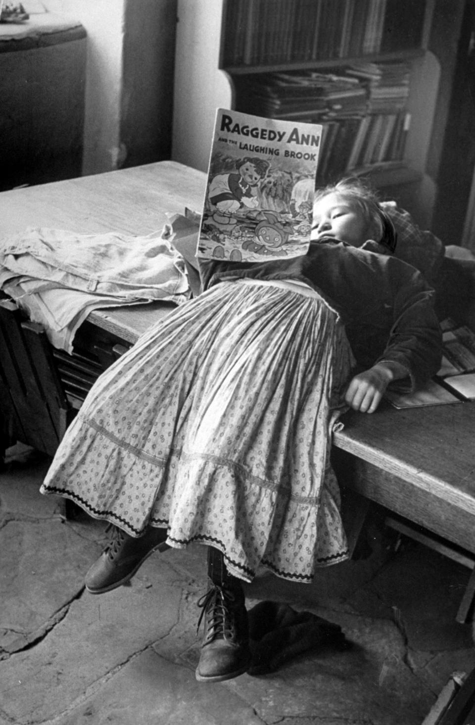 A young Navajo girl reading a Raggedy Ann book.