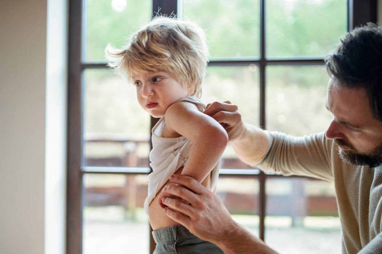 A man examines a young child’s lower back.