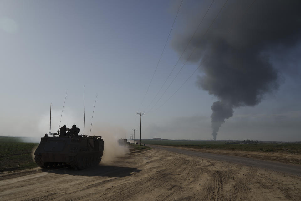 Israeli soldiers travel on an army armored personnel carriers (APC) near the Israeli-Gaza border as smoke rises to the sky in the Gaza Strip, seen from southern Israel, Sunday, Jan. 21, 2024. (AP Photo/Leo Correa)