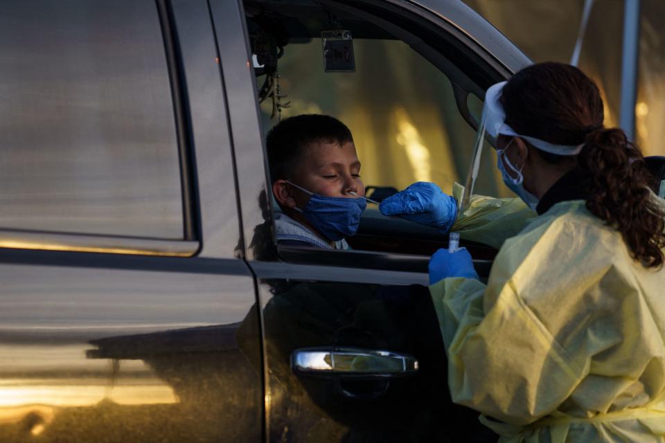 A health care worker collects a nasal swab sample from a young boy.