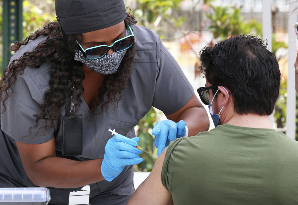 FILE - In this June 17, 2021, file photo, an Orange County resident receives the COVID-19 vaccine at the Florida Division of Emergency Management mobile vaccination site at Camping World Stadium in Orlando, Fla. COVID-19 deaths in the U.S. have dipped below 300 a day for the first time since the early days of the disaster in March 2020, while the number of Americans fully vaccinated has reached about 150 million. (Joe Burbank/Orlando Sentinel via AP, File)