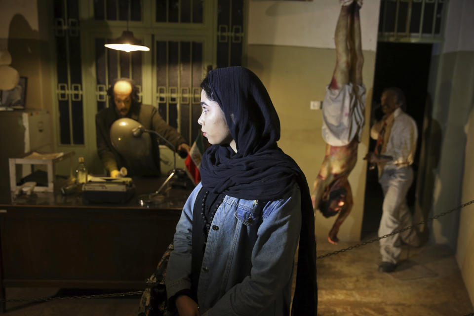 In this Jan. 7, 2019 photo, an Iranian looks at an exhibition at a former prison run by the pre-revolution intelligence service, Savak, now a museum, where wax mannequins of interrogators and a prisoner are displayed, in downtown Tehran, Iran. As Iran marks the 40th anniversary of its Islamic Revolution and the overthrow of the shah, those who suffered torture at the hands of the police and dreaded SAVAK intelligence service still bear the scars. U.N. investigators and rights group say that even today, Iran tortures and arbitrarily detains prisoners. (AP Photo/Ebrahim Noroozi)