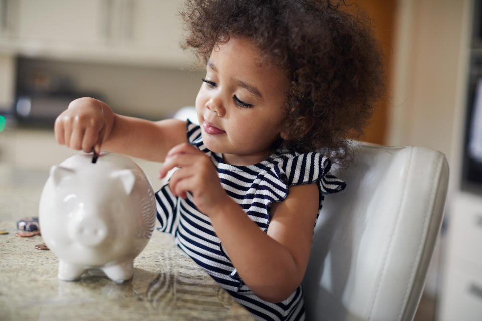 Little toddler girl saving money in her piggy bank