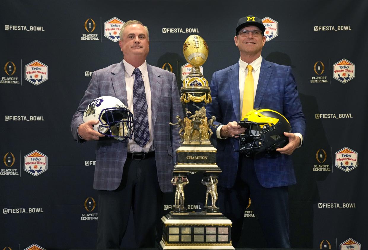 TCU Horned Frogs head coach Sonny Dykes and Michigan Wolverines head coach Jim Harbaugh pose in front of the Fiesta Bowl trophy during the Vrbo news conference at Camelback Inn before Saturday's bowl game.