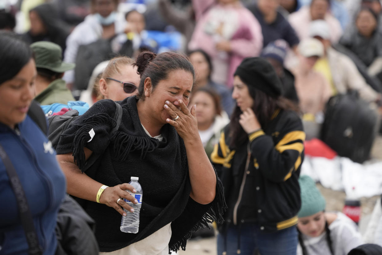 A woman cries as she is chosen by U.S. Border Patrol agents to be taken to processing after waiting for days between two border walls to apply for asylum, Friday, May 12, 2023, in San Diego. The border between the U.S. and Mexico was relatively calm Friday, offering few signs of the chaos that had been feared following a rush by worried migrants to enter the U.S. before the end of pandemic-related immigration restrictions. (AP Photo/Gregory Bull)