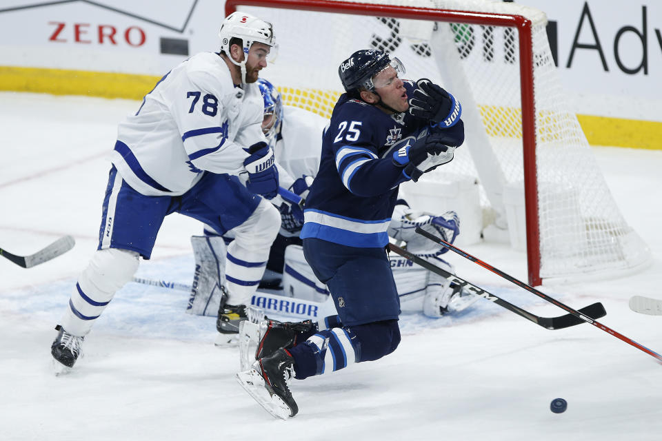 Winnipeg Jets' Paul Stastny (25) goes down after getting a high stick to the face from Toronto Maple Leafs' TJ Brodie (78) during the second period of an NHL hockey game Wednesday, March 31, 2021, in Winnipeg, Manitoba. (John Woods/The Canadian Press via AP)