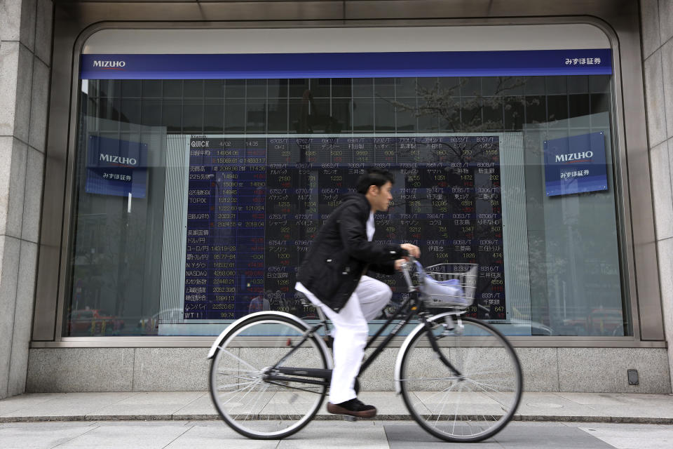 A man rides a bicycle past an electronic stock board of a securities firm in Tokyo Wednesday, April 2, 2014. Asian stock markets pushed higher Wednesday on signs of a pickup in the U.S. economy and expectations of further stimulus in Japan. Tokyo's Nikkei 225 closed at 14,946.32, after gaining 154.33 points, or 1.04 percent. (AP Photo/Eugene Hoshiko)