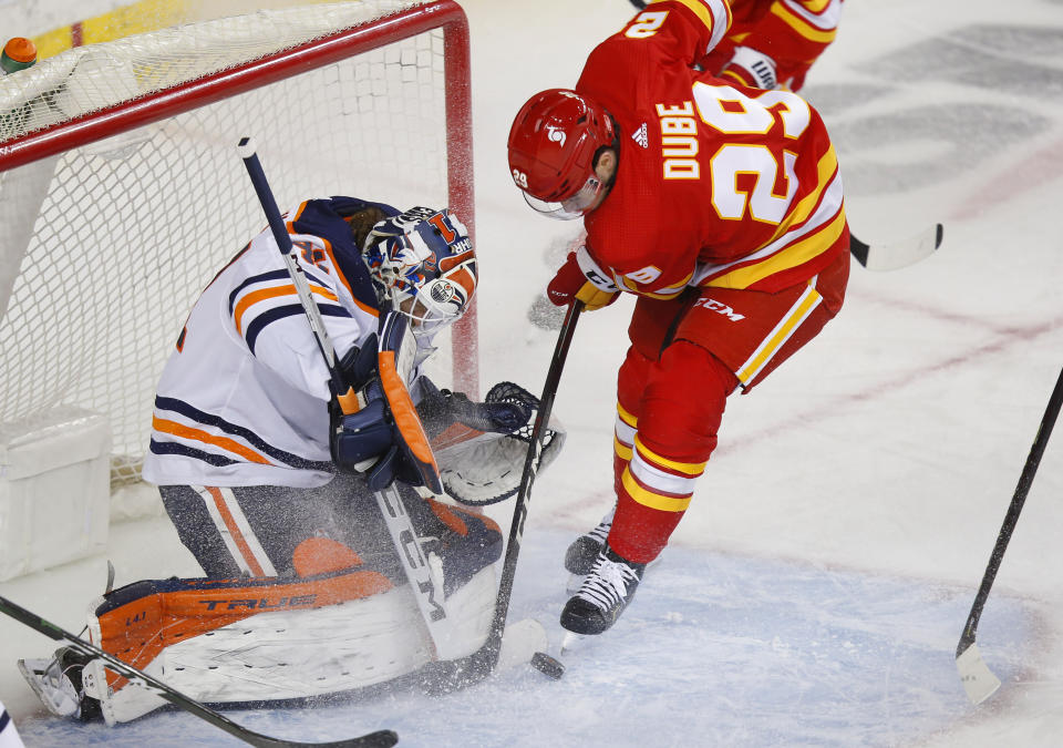 Edmonton Oilers goalie Mike Smith makes a save on Calgary Flames' Dillon Dube during the first period of an NHL hockey game, Friday, Feb. 19, 2021 in Calgary, Alberta. (Todd Korol/The Canadian Press via AP)