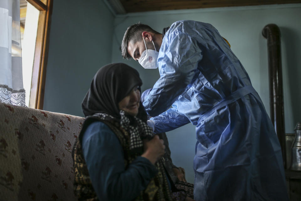 Zeynep Yigit, 70, left, is administered a dose of the CoronaVac vaccine made by China's Sinovac Biotech Ltd., by health worker Yusuf Duran at her house in the isolated village of Gumuslu in the district of Sivas, central Turkey, Friday, Feb. 26, 2021. Health care workers, older people and people with serious medical conditions were among the first to receive the jab. (AP Photo/Emrah Gurel)