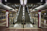 FILE - In this Wednesday, March 11, 2020, a man wearing a mask descends an escalator at a deserted subway station in Milan, Italy. The eurozone's third-largest economy and a major exporter, Italy on Wednesday becomes the first western industrialized nation to idle swaths of industrial production to stop the spread of coronavirus by keeping yet more of the population at home. The new coronavirus causes mild or moderate symptoms for most people, but for some, especially older adults and people with existing health problems, it can cause more severe illness or death. (Claudio Furlan/LaPresse via AP)