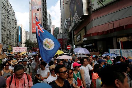 A protester carries a former colonial flag during a march in Hong Kong, China, July 1, 2018, the day marking the 21st anniversary of the city's handover to Chinese sovereignty from British rule. REUTERS/Bobby Yip