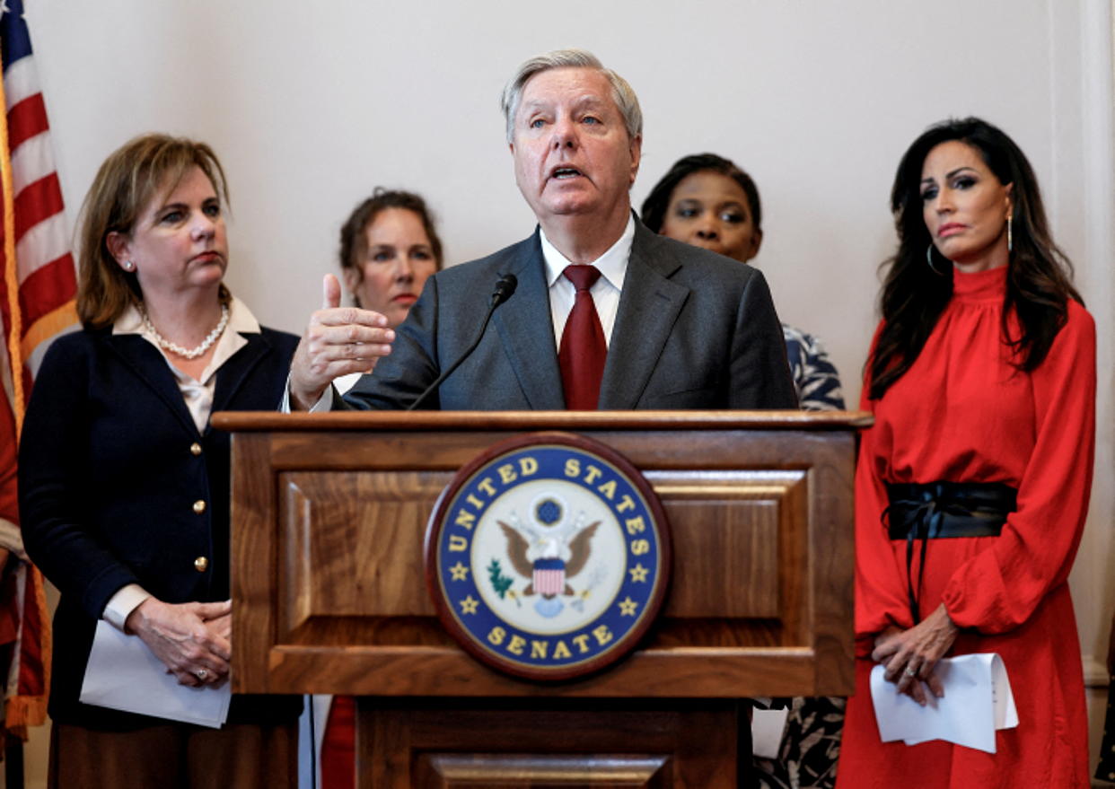 Sen. Lindsey Graham, surrounded by four women, at a podium marked United States Senate.