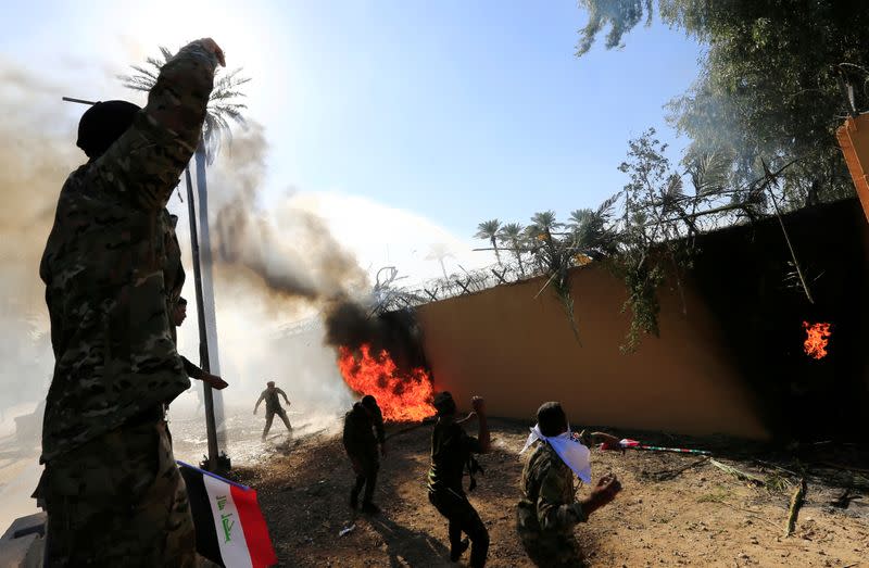 Combatientes de Hashd al-Shaabi (fuerzas paramilitares) prendieron fuego al muro de la embajada de Estados Unidos para condenar los ataques aéreos a sus bases, en Bagdad, Irak, el 31 de diciembre de 2019