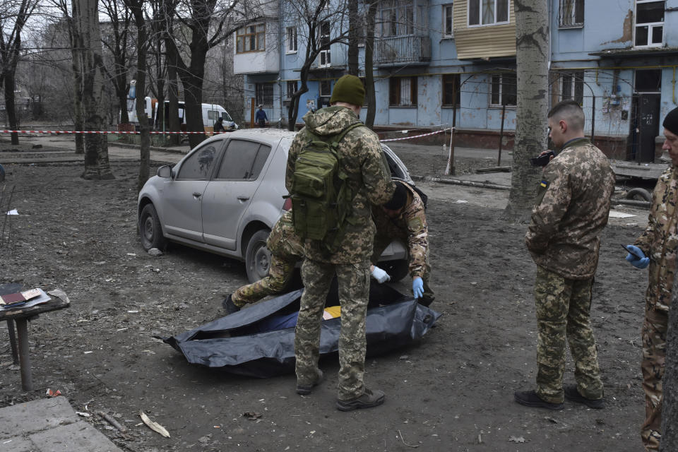 Police inspect the lifeless body of a local resident killed as a Russian missile hit an apartment house during a Thursday night missile attack in Zaporizhzhia, Ukraine, Friday, March 3, 2023. At least five people were killed. (AP Photo/Andriy Andriyenko)