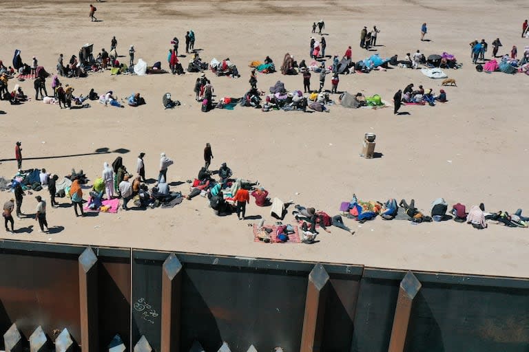 Una imagen aérea muestra a migrantes esperando a lo largo del muro fronterizo para entregarse a los agentes de la patrulla fronteriza de Aduanas y Protección Fronteriza (CBP) de EE. UU. para el procesamiento de solicitudes de inmigración y asilo después de cruzar el río Grande hacia Estados Unidos, en la frontera entre EE. UU. y México en El Paso, Texas, el 11 de mayo de 2023.